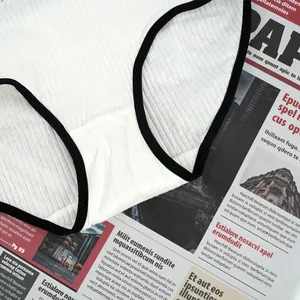 Detail of white ribbed cotton panties with black contrast trim on vintage newspaper
