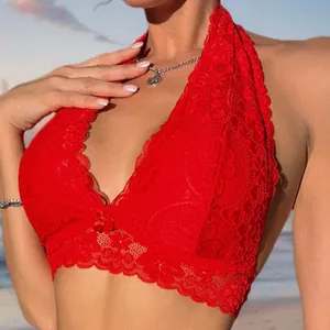Close-up of red lace halter bralette with floral patterns and a front bow on a beach
