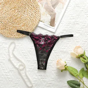 Detail of black lace thong featuring purple floral embroidery and adjustable waist straps