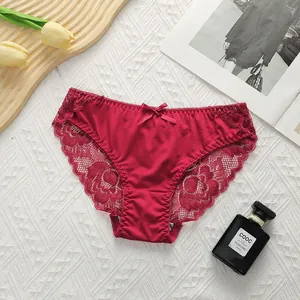 Close-up of deep red lace panties with floral patterns and a small bow on white background