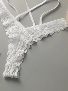 Détail de culotte en dentelle blanche avec broderie florale et fines bretelles croisées