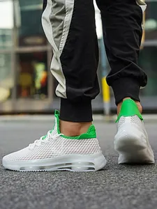 Detail van witte mesh sportschoen met groene accenten en een dikke, gedempte zool