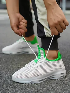 Detail van witte mesh ademende sneakers met groene accenten en een zool met luchtkussen