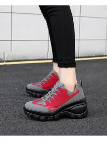 Buitenaanzicht van dikke sneakers met rood en grijs gaas op plateauzolen van de zijkant
