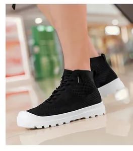 Close-up of black breathable knit sneakers with thick white rubber soles on a male model