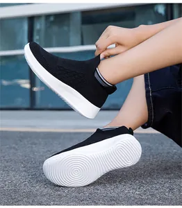 Detail view of breathable fly-knit mesh fabric and white non-slip sole on black sneakers