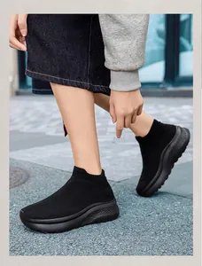 Sneakers a calzino in maglia nera con suola spessa indossate su pavimentazione urbana