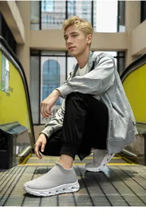 Close-up of light grey flyknit slip-on sneakers with white hollowed thick sole