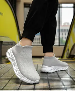Detail of grey knitted sock sneakers with white wavy thick soles on an escalator