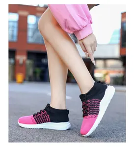 Outdoor opname van roze en zwarte gebreide sneakers met dikke witte zolen in stad