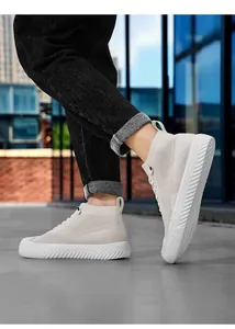 Close-up of beige knitted high-top sneakers with thick anti-slip rubber soles on street