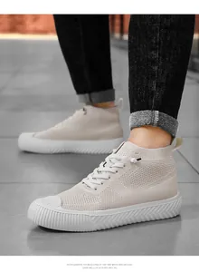 Detail view of beige knitted high-top sneakers with thick rubber soles and breathable fabric