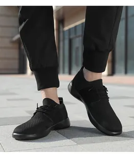 Dettaglio di sneakers in maglia nera traspirante da uomo con suola spessa in strada