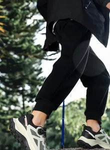Detailed view of outdoor hiking shoes with rotary lace system and black joggers