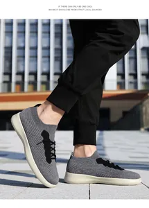 Vue extérieure de baskets en tricot gris avec lacets noirs et semelles blanches épaisses