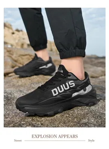 Primer plano de zapatos de senderismo negros transpirables con logo DUUS en suelo rocoso