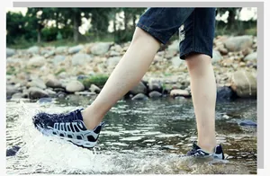 Blauwe mesh waterschoenen met drainagegaten tijdens een wandeling door een beekje