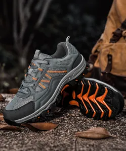 Detail von atmungsaktiven Wanderschuhen mit Mesh und orangefarbenen Akzenten auf Kies