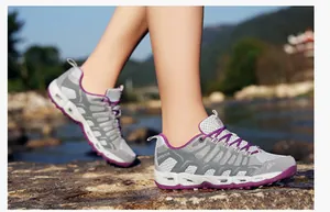 Detail van ademende wandelschoenen met drainagegaten op rotsen bij de rivier