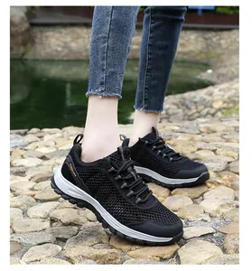 Outdoor shot of breathable black hiking sneakers with orange details and mesh texture