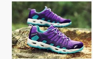 Detail van paarse en groenblauwe wandelschoenen met ademend mesh op natuurlijke rotsen