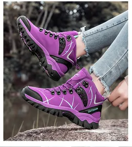 Outdoor action shot of purple high-top hiking boots with deep tread rubber soles on rocks