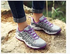 Detail van ademende grijze mesh wandelschoenen voor dames met paarse veters op rotsen