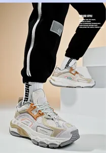 Dettaglio di sneaker chunky retrò beige in mesh e pelle scamosciata indossate da modello
