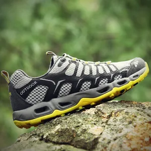 Outdoor wandelschoenen met ademend grijs mesh en antislip gele zolen op rotsen