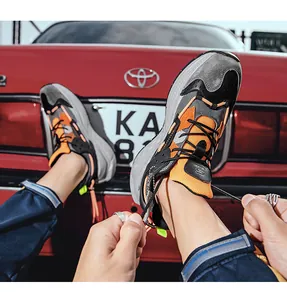 Nahaufnahme der Leder-Patchwork-Chunky-Sneaker mit orangefarbenen Akzenten und Schnürsenkeln
