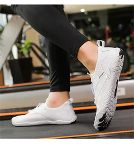 Dettaglio scarpe anfibie in mesh bianco con suola a cinque dita su un tapis roulant