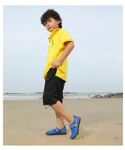 Blaue Kinder-Wasserschuhe mit gelber rutschfester Sohle am Strand zum Schwimmen und Wandern