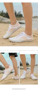 Gros plan de chaussures d'eau blanches avec motifs orange sur une plage de sable