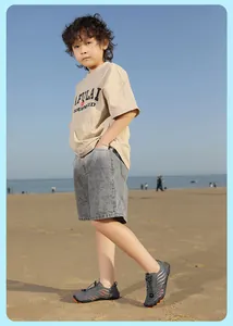 Outdoor view of children's grey quick-dry water shoes with orange stripes on a beach
