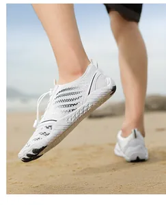 Close-up of white breathable water shoes with black wave stripes on a sandy beach