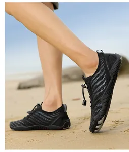 Outdoor shot of black water shoes with breathable mesh and quick-lace system on sand