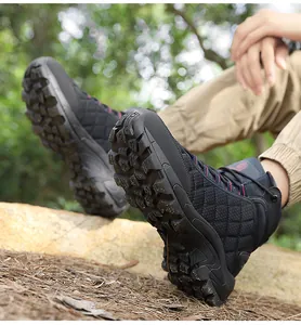 Detail of durable non-slip rubber outsole on black outdoor hiking boots in the woods