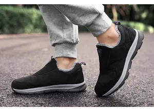 Vue portée de baskets noires sans lacets avec doublure chaude pour la marche dehors