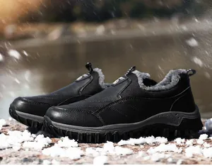 Close-up of black men's winter snow boots with thick faux fur lining in snowy outdoor setting