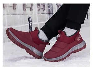 Détail macro de bottes d'hiver bordeaux imperméables avec doublure en laine chaude dans la neige