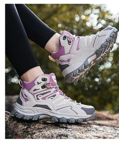 Close-up of women's hiking boots with purple mesh details on a rocky outdoor terrain