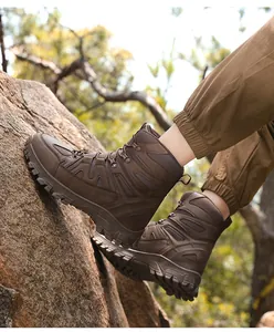 Makroaufnahme brauner taktischer Stiefel mit tief profilierter Gummisohle auf Felsboden