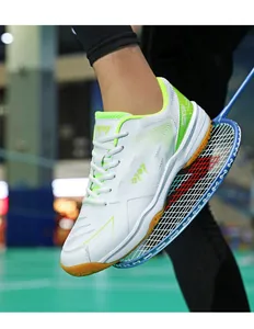 Dettaglio delle scarpe da badminton bianche con accenti verdi su un campo indoor