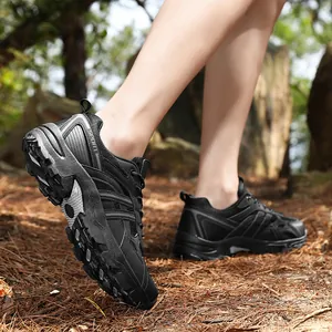 Rugged black outdoor hiking shoes with rubber grip soles on a forest floor surface
