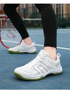 Close-up of breathable white mesh tennis shoes with green soles on a court court