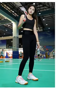 Donna in completo sportivo nero e scarpe rosa-bianche che gioca a badminton in campo
