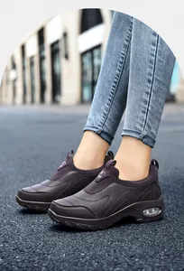 Detail of dark brown leather slip-on sneakers featuring cushioned air soles and purple pull tab