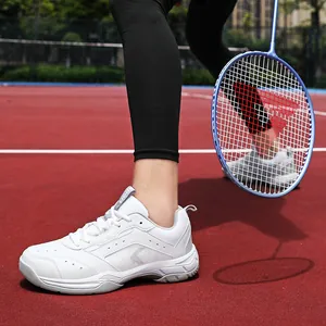 Weiße atmungsaktive Mesh-Sportschuhe für Badminton und Laufen auf einem roten Platz