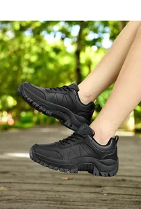 Outdoor close-up of chunky black hiking sneakers with durable thick rubber anti-slip soles