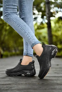 Close-up of black breathable mesh sneakers with clear air cushion heel on wooden path